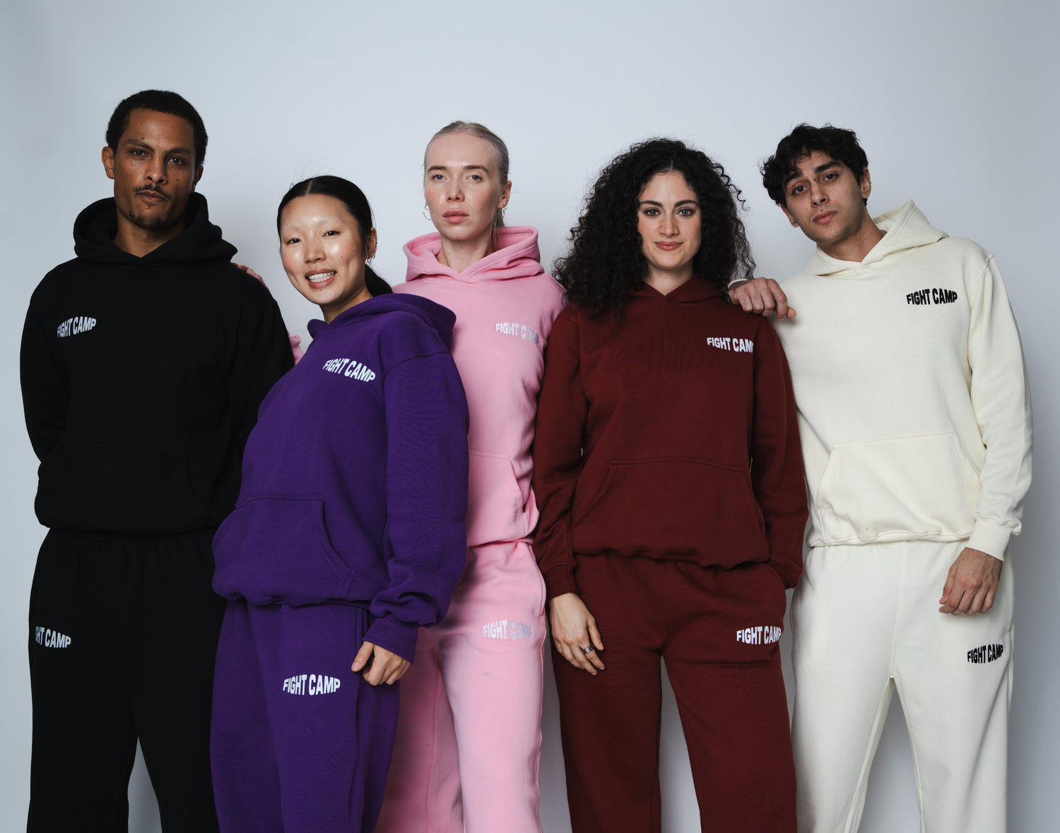 Five people wearing matching hoodie and pants sets from a brand on a white background